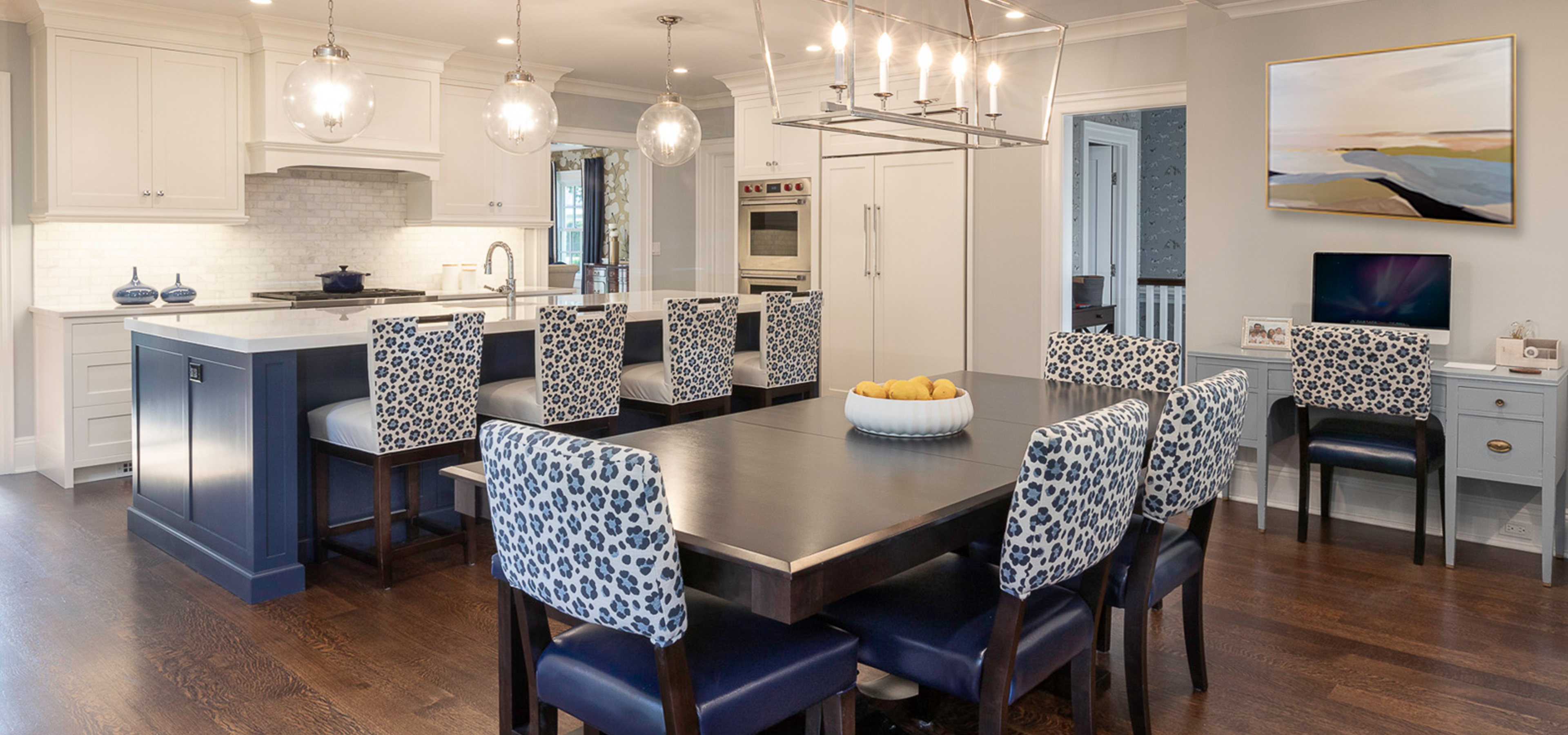 A dining room table with blue chairs and a bowl of fruit.